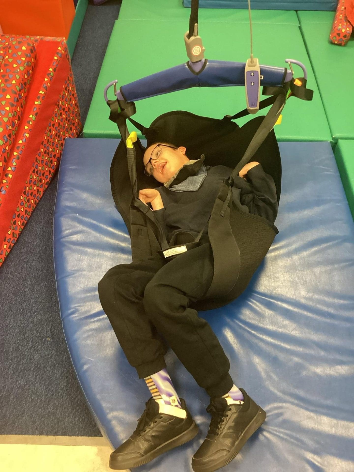 Student using ceiling-track hoist system in sensory room at SEND secondary school